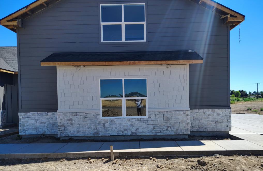 Exterior painting project with gray siding white shingle accents and stone base in Twin Falls Idaho
